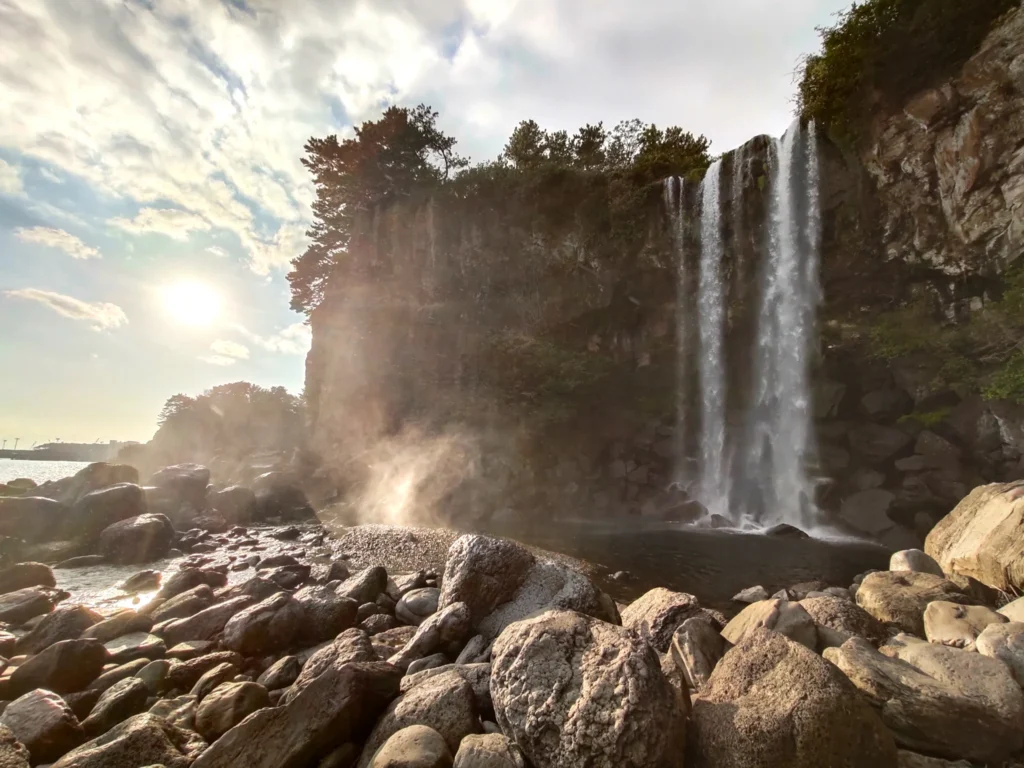 Vue spectaculaire de la cascade Jeongbang à Jeju, Corée du Sud, l'une des rares cascades au monde se jetant directement dans l'océan. Admirez la beauté impressionnante de la cascade Jeongbang à Jeju, unique en son genre en se jetant directement dans l'océan. Une attraction naturelle incontournable lors de notre voyage en Corée du Sud avec Evans Becker. En savoir plus sur Go Corée.