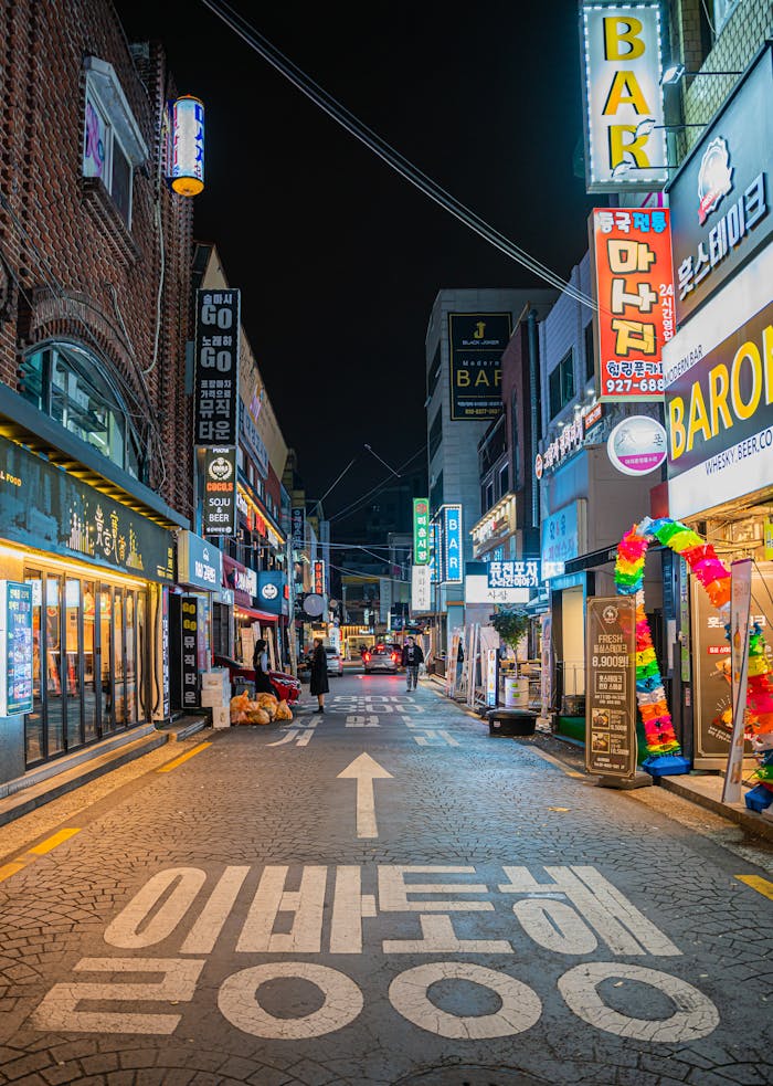 Rue animée de Myeongdong de nuit à Séoul, Corée du Sud, éclairée par des néons et remplie de passants, Plongez dans l'ambiance vibrante de Myeongdong de nuit, l'un des quartiers les plus animés de Séoul, avec ses boutiques éclairées par des néons et ses stands de street food. Une expérience nocturne incontournable lors de notre voyage en Corée du Sud avec Evans Becker. En savoir plus sur Go Corée.