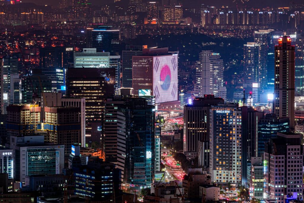 ue panoramique de la ville de Séoul de nuit, illuminée par les lumières de la ville et ses gratte-ciels, Admirez la vue spectaculaire de Séoul de nuit, avec ses gratte-ciels illuminés et son paysage urbain vibrant. Une expérience visuelle impressionnante lors de notre voyage en Corée du Sud avec Evans Becker. Découvrez plus sur Go Corée.